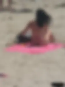 Brunette lady topless and in a black thong on the beach