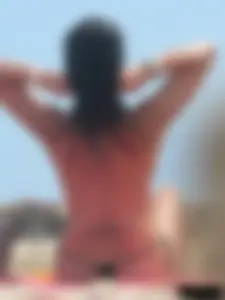 Brunette lady topless and in a black thong on the beach