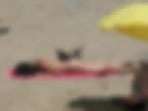 Brunette lady topless and in a black thong on the beach
