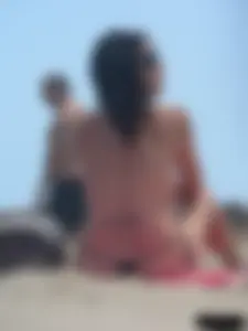 Brunette lady topless and in a black thong on the beach