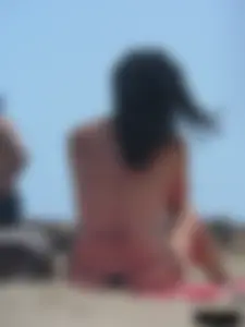 Brunette lady topless and in a black thong on the beach