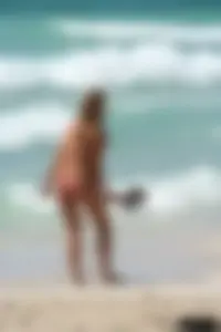 Topless girl in a tiny thong on the beach playing paddle ball