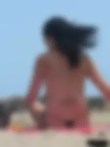 Brunette lady topless and in a black thong on the beach