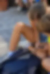 Cute skinny candid teen in denim shorts sitting on the pavement on the street