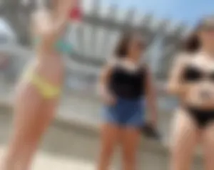 Sexy beach babe in yellow and blue bikini with friends