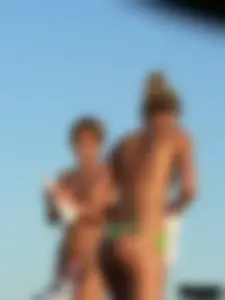 Topless girl on the beach with small boobs wearing a green thong bikini