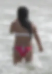 Brunette bikini girl on the beach and surfing in her bikini