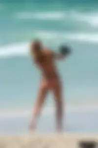 Topless girl in a tiny thong on the beach playing paddle ball
