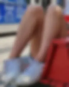 Girl in mini shorts lying on a bench at the bus stop
