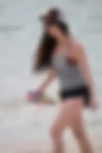 Brunette girl in black shorts and bikini top on the beach