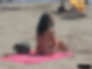 Brunette lady topless and in a black thong on the beach