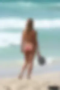 Topless girl in a tiny thong on the beach playing paddle ball