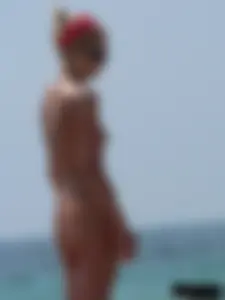 Topless skinny blonde lady in a g-string bikini at the beach