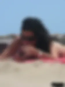 Brunette lady topless and in a black thong on the beach