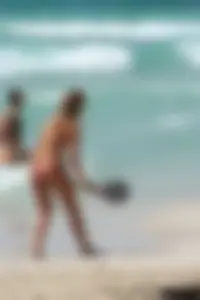 Topless girl in a tiny thong on the beach playing paddle ball