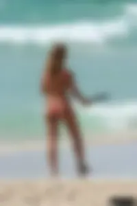 Topless girl in a tiny thong on the beach playing paddle ball
