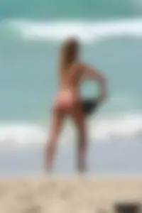 Topless girl in a tiny thong on the beach playing paddle ball
