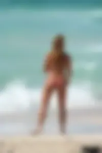 Topless girl in a tiny thong on the beach playing paddle ball