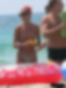 Topless skinny blonde lady in a g-string bikini at the beach