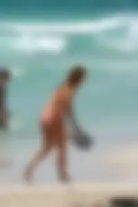 Topless girl in a tiny thong on the beach playing paddle ball