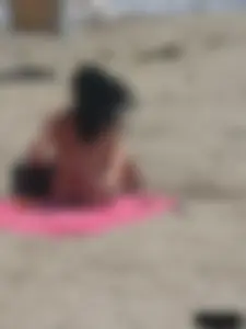 Brunette lady topless and in a black thong on the beach