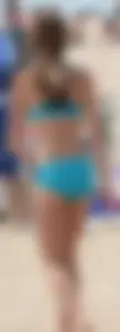 Sexy and petite girl playing volleyball on the beach in a blue bikini
