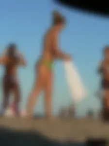Topless girl on the beach with small boobs wearing a green thong bikini