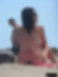 Brunette lady topless and in a black thong on the beach