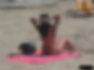 Brunette lady topless and in a black thong on the beach