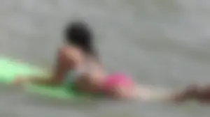 Brunette bikini girl on the beach and surfing in her bikini
