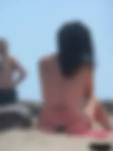 Brunette lady topless and in a black thong on the beach
