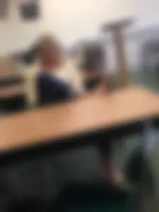 College teen in slippers sitting at her desk with one leg put on table