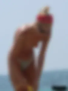 Topless skinny blonde lady in a g-string bikini at the beach