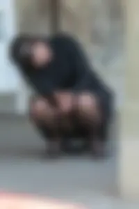 Candid girl wearing black pantyhose, a skirt and high heels squatting on the street flashing her panties
