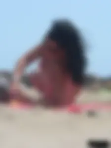 Brunette lady topless and in a black thong on the beach