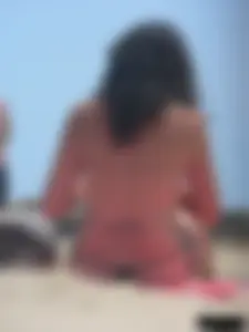 Brunette lady topless and in a black thong on the beach