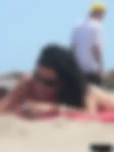 Brunette lady topless and in a black thong on the beach