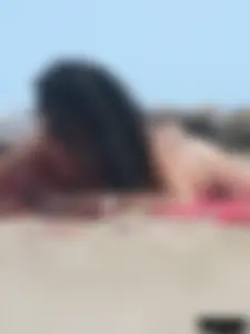 Brunette lady topless and in a black thong on the beach