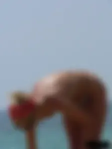 Topless skinny blonde lady in a g-string bikini at the beach