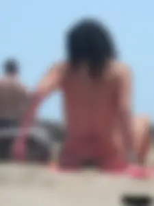 Brunette lady topless and in a black thong on the beach