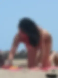 Brunette lady topless and in a black thong on the beach