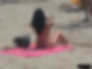 Brunette lady topless and in a black thong on the beach