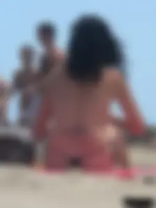 Brunette lady topless and in a black thong on the beach