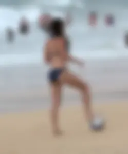Hottie bikini babe on the beach kicking around a volleyball