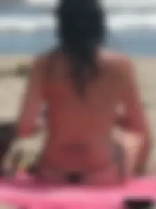 Brunette lady topless and in a black thong on the beach