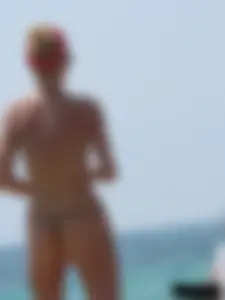 Topless skinny blonde lady in a g-string bikini at the beach