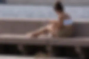 Cute candid girl took off her sandals and sat on a bench to read