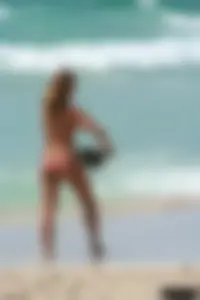 Topless girl in a tiny thong on the beach playing paddle ball