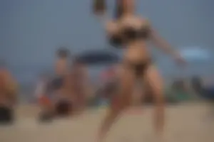 Sexy brunette in bikini playing football on the beach