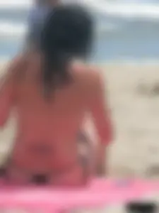 Brunette lady topless and in a black thong on the beach